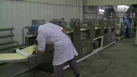 A male worker monitors the operation of an automatic noodle production line Stock Footage 149072665
