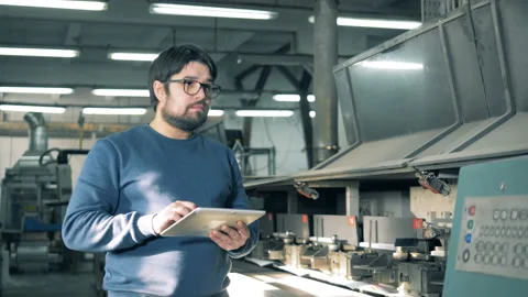 Male worker is observing a functioning printing machine Stock Footage 104202659