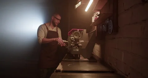 Male worker operating lathe machine in dark garage Stock Footage 259391848