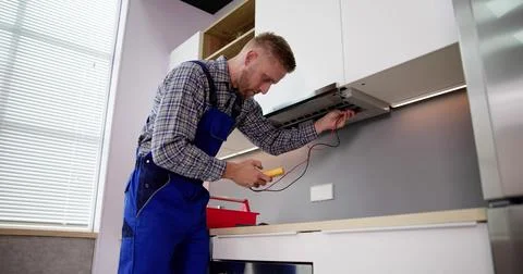 Male Worker In Overall Testing Kitchen Hood With Multimeter Stock Photos