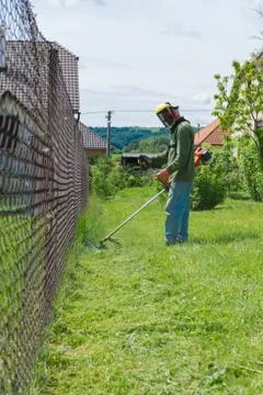 Male worker with power tool string lawn trimmer mower cutting grass Stock Photos
