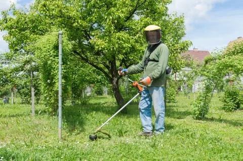 Male worker with power tool string lawn trimmer mower cutting grass Stock Photos