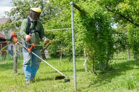 Male worker with power tool string lawn trimmer mower cutting grass Stock Photos