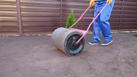 Male worker prepares a plot of land for sowing a lawn using a garden roller Vídeos de archivo 290166346