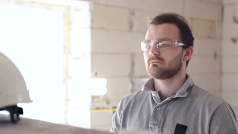 A male worker puts on a white construction helmet on a construction site. Stock Footage 160887476