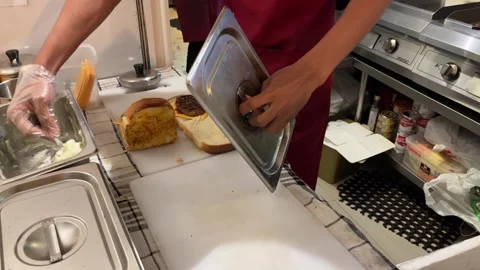 A male worker in red apron preparing beef sandwich Stock Footage 243359170