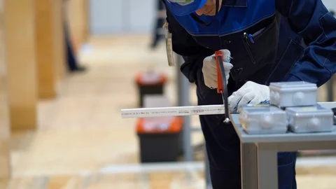 Male worker standing at table, use hacksaw, saw off piece of cable channel Stock Footage 126357617