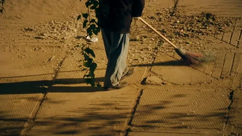 Male worker sweeps a pedestrian path in the early morning Stock Footage 155669530