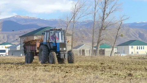 Male worker on tractor with trailer going around field Stock Footage 75439111