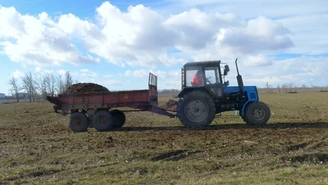 Male worker on tractor with trailer going around field Stock Footage 75439413