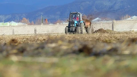 Male worker on tractor with trailer going around field Stock Footage 75441309