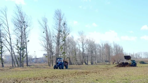 Male worker on tractor with trailer going around field Stock Footage 75444573