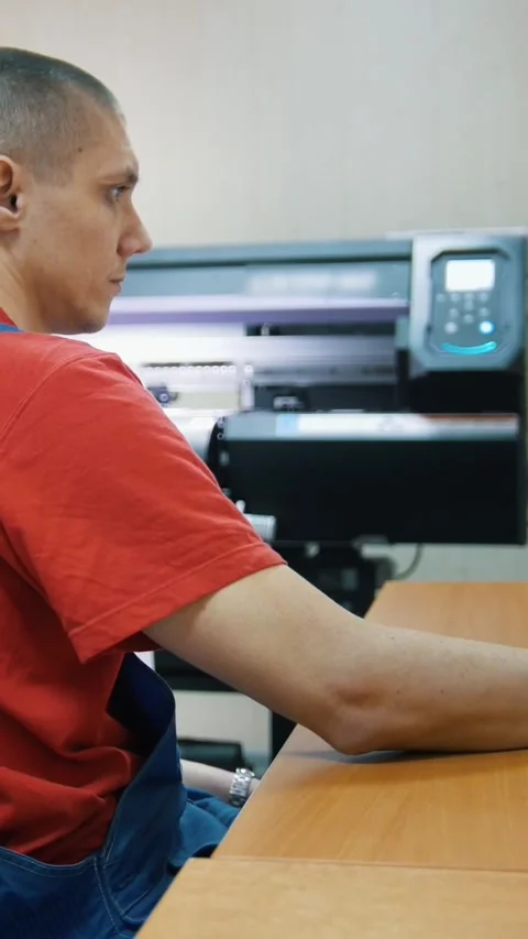 Male worker in typography with computer in front of printing press Stock Footage 346706440