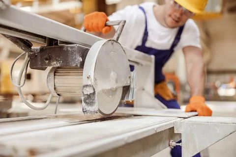 Male worker using sawing machine in workshop Stock Photos