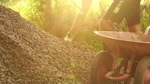 A male worker is using a shovel to dig stones to build his house Stock Footage 199632540