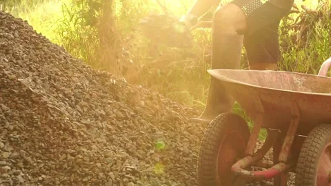 A male worker is using a shovel to dig stones to build his house Stock Footage 199632586