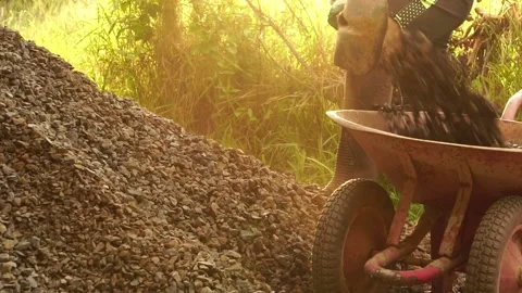 A male worker is using a shovel to dig stones to build his house Stock Footage 199632588