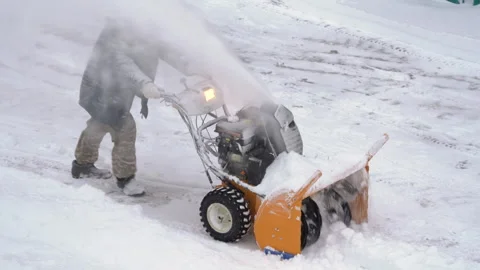 Male worker is using snowblower to remove snow after winter cyclone. Worker is Stock Footage 259862370