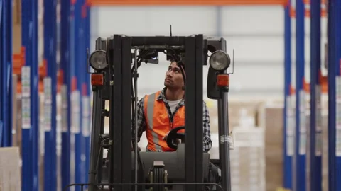 A male worker in the warehouse looking up while using a forklift to move pr.. Stock Footage 264082943