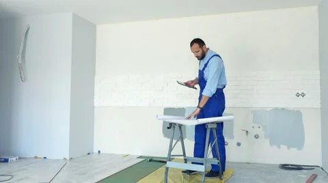 Male worker wcomparing data on tablet and blueprints at new home Stock Footage 63238214