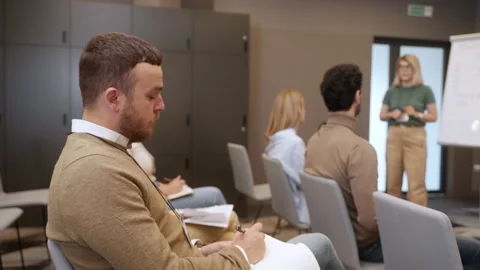 Male worker writing down notes from a conference, sitting on a chair Stock-Footage 218615814