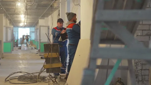 Male workers actively work on wall fixture while observing Stock Footage 311107136