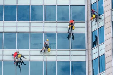 Male workers cleaning skyscraper windows in urban setting Foto stock