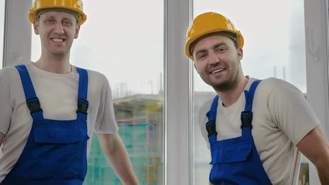 Male workers engineers in helmets look into the camera and smile, at a Stock-Footage 113766983