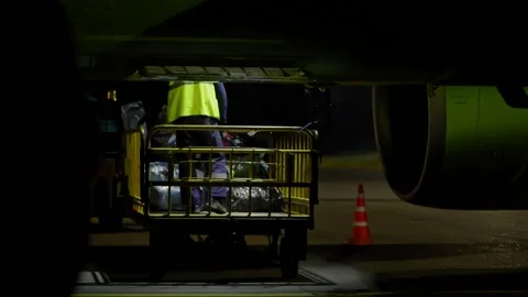Male workers loading baggage onto airplane and working at airport outdoors. Vídeos de archivo 157942641