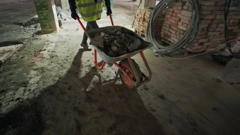 Male workers stack pieces of concrete floor into a wheelbarrow Stock Footage 264422167