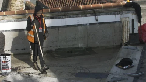 Male Workman Applying Bitumen Mastic On Roof Flat Of Building In London. Stock Footage 149300528