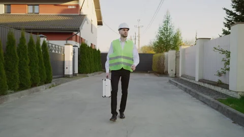 Male workman in hard hat carrying toolbox after doing repair work in the house Stock Footage 242588122