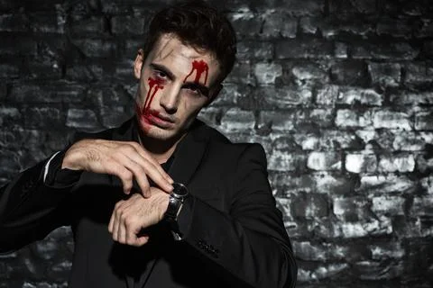 Male zombie posing at camera, while checking time Stock Photos