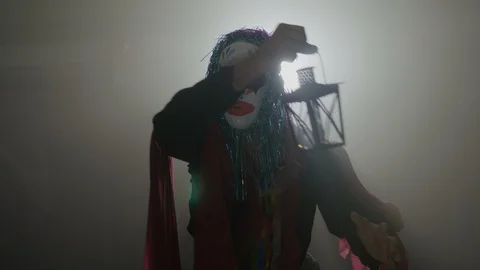 Malefic clown coming out from the dark fog dancing on halloween with a lamp i Stock Footage 86564408