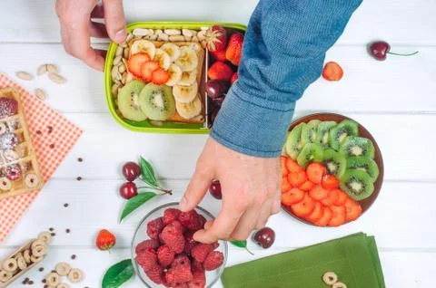 Males hands picking up a raspberry for lunch box Stock Photos