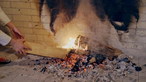 Male's hands split the heat with a log in the fire indoors. Close-up hands Stock Footage 111422907