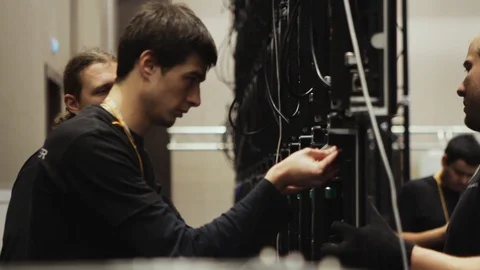 Males tech workers construct black screen panel during display installation. Stock Footage 119517699