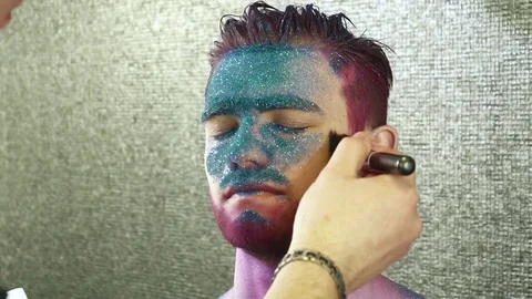 Maleup artist creating a body art for a young man slow motion Stock Footage