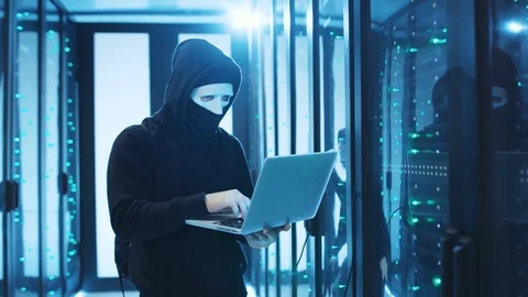 Malicious hacker in mask breaking into database server room, turning off power Stock Footage 120695183