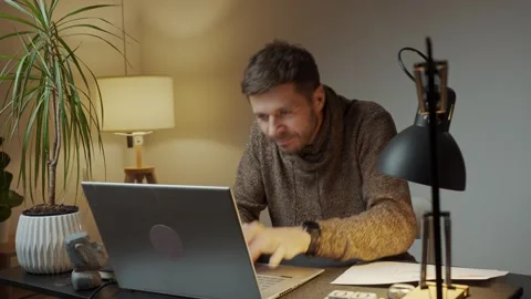 Maliciously smiling man rubbing his hands in front of laptop screen Stock Footage 322086989