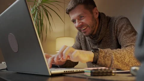 Maliciously smiling man rubbing his hands and typing on laptop keyboard Stock Footage 323053203