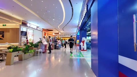 Mall interior with curved ceiling, tiled floor, and various shops. Video stock 287001382