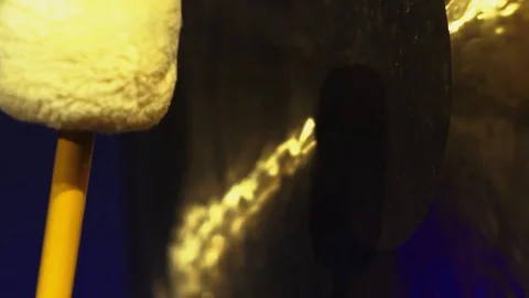 Mallet close-up hitting a big gong with in a dark room. Stock Footage 100561114