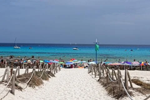 Mallorca, path to the beach of Cala Agulla with green flag and blue sky and sea Stock Photos