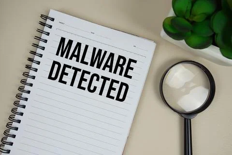 Malware Detected text on paper notebook with magnifying glass on beige leat.. Stockfoto's