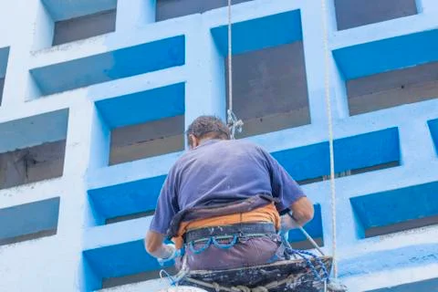 Malyak on the ropes painting the wall Stock Photos