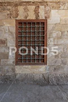 Mamluk era wooden closed window with wooden ornate grid over stone wall Stock Photos