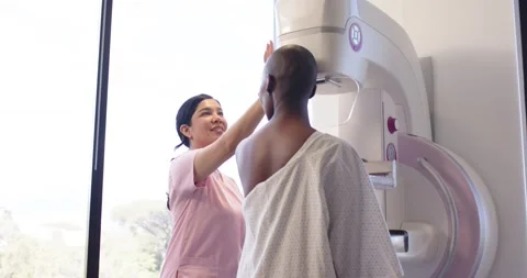 Mammo tech in pink scrubs greeting African American woman at unit guiding Stock Footage 336174600