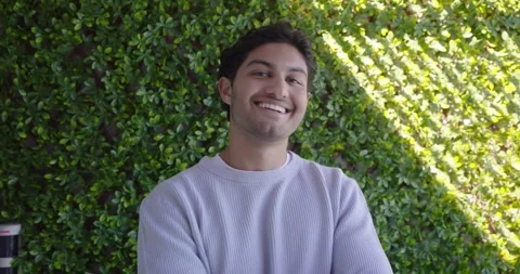 Man 20s camera drawing gaze, smiling then laughing, crossing into gaze in Stock Footage 339678605