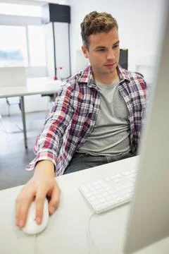 Man in 20s sitting in workspace using computer with keyboard and wired mouse, Stock Photos